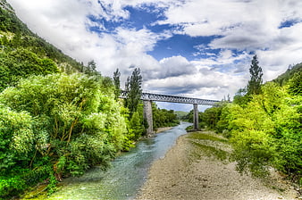 Scenic metal bridge over river in lush green valley
