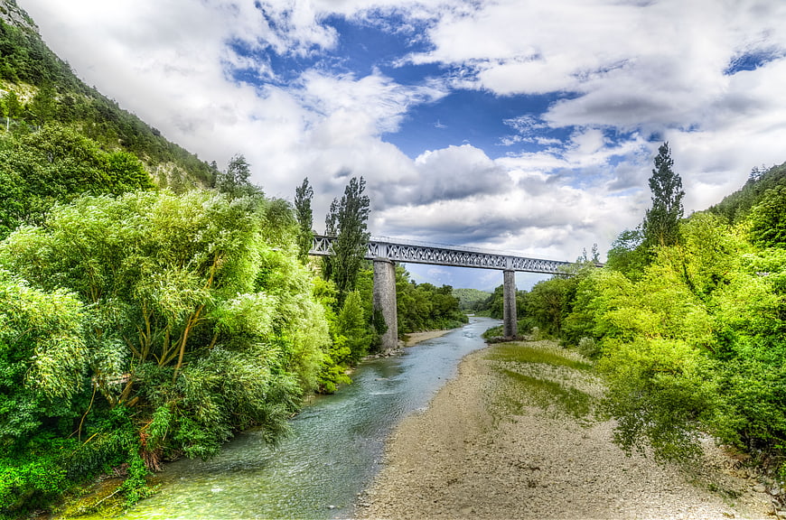 Scenic metal bridge over river in lush green valley