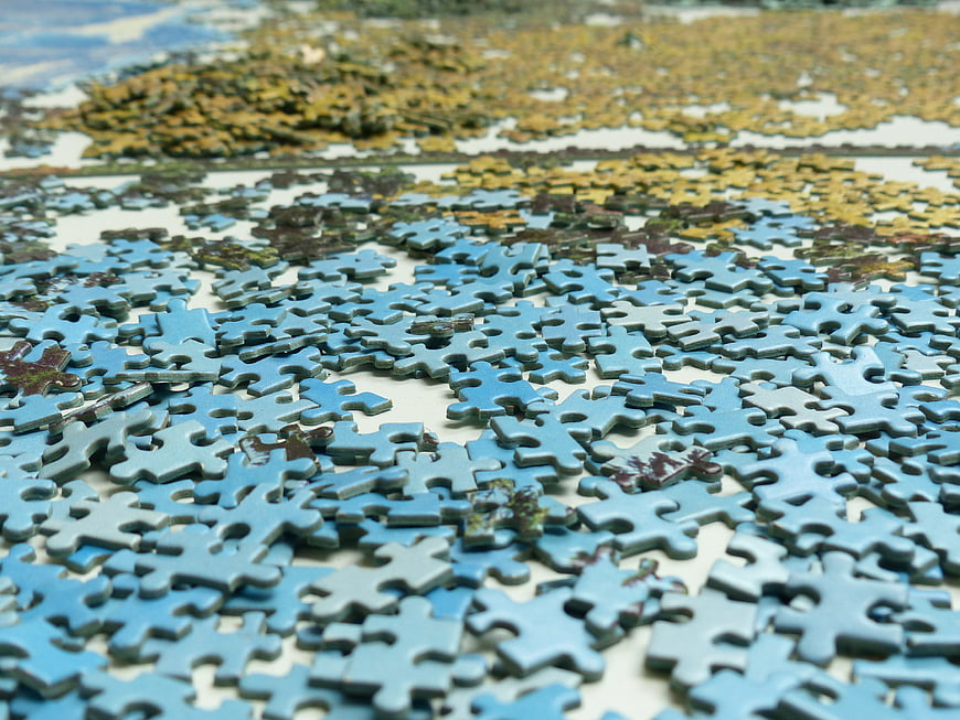Scattered Blue Jigsaw Puzzle Pieces On White Surface