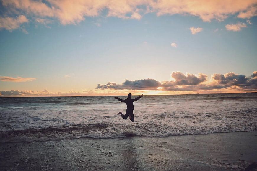 Silhouette of Person Jumping on Beach at Sunset