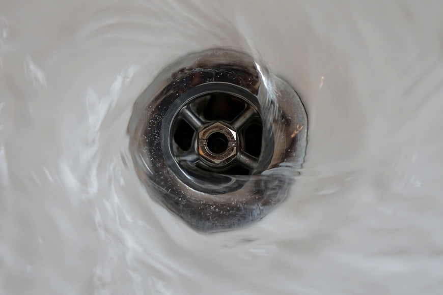 Top Down View Of Bathroom Sink Drain With Swirling Water
