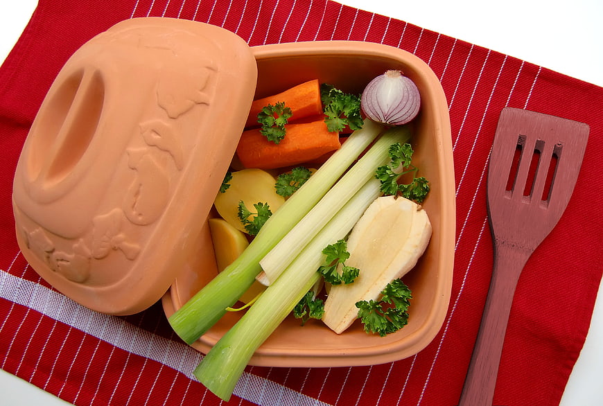 Roman Pot With Fresh Vegetables And Wooden Spatula On Red Cloth