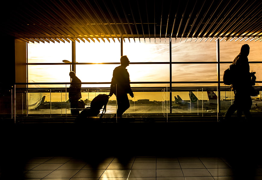 Silhouettes of travelers walking in airport terminal at sunset