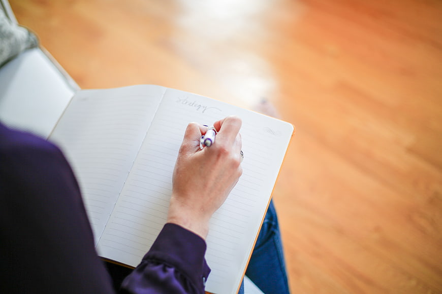 Woman Writing Strategy in Notebook on Wooden Floor