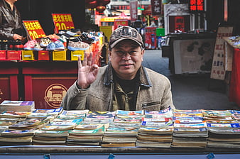 Friendly elderly Chinese man selling books at outdoor market