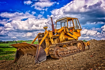 Yellow Bulldozer on Construction Site Under Dramatic Cloudy Sky