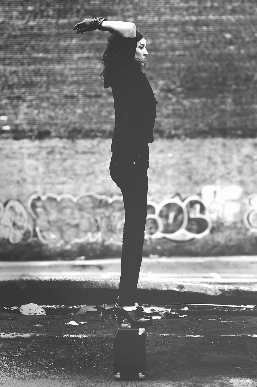 Woman balancing on suitcase in urban black and white photo