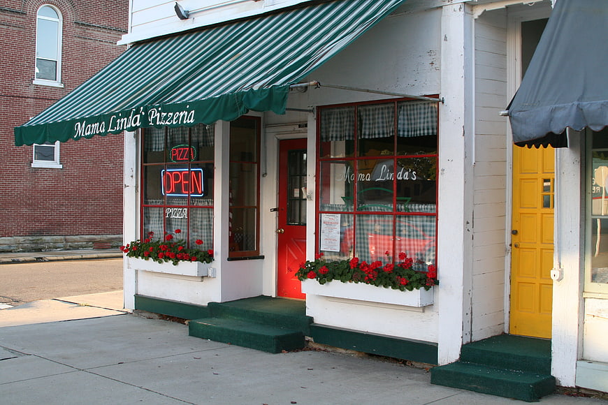Mama Linda's Pizzeria storefront with green awning and red flowers