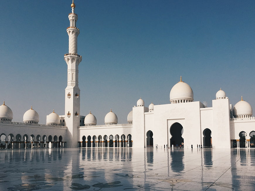 White Mosque with Minaret and Domes Reflecting in Courtyard