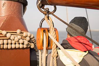 Sailor on Traditional Wooden Sailboat with Pulley and Ropes