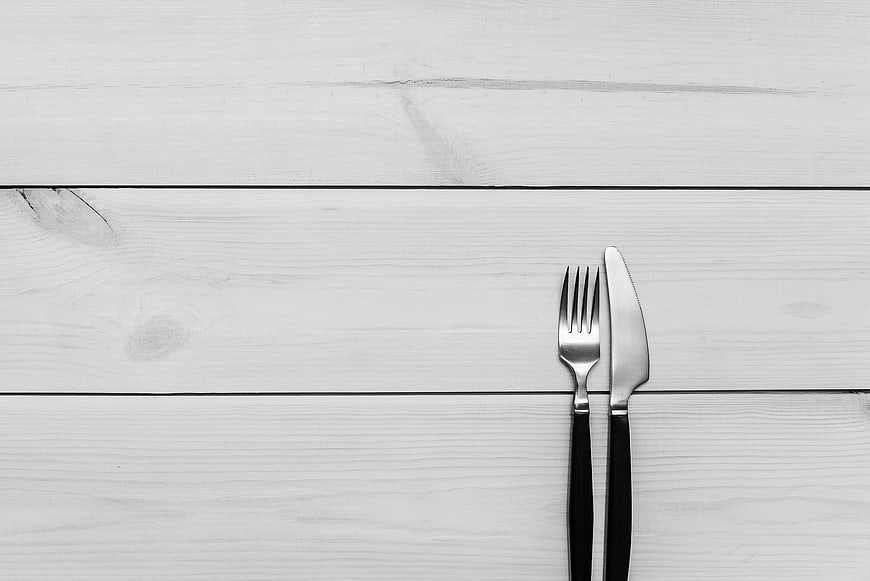 Minimalist black and white cutlery on white wooden table