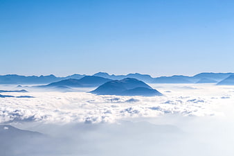 Aerial view of mountains rising above a sea of clouds