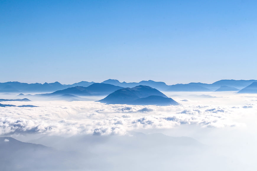 Aerial view of mountains rising above a sea of clouds