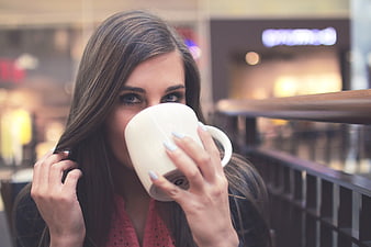 Woman drinking coffee in a cafe with blurred background