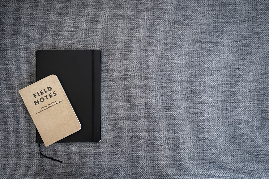 Minimalist black notebook and field notes on gray textured background