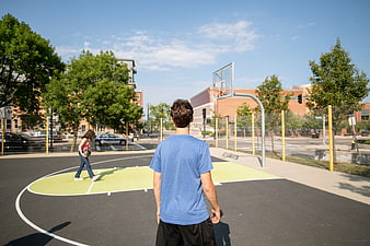 Young man and woman playing basketball on urban court