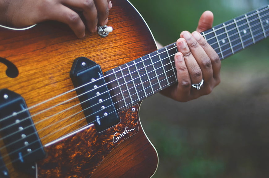 Close-up of hands playing a Godin electric guitar