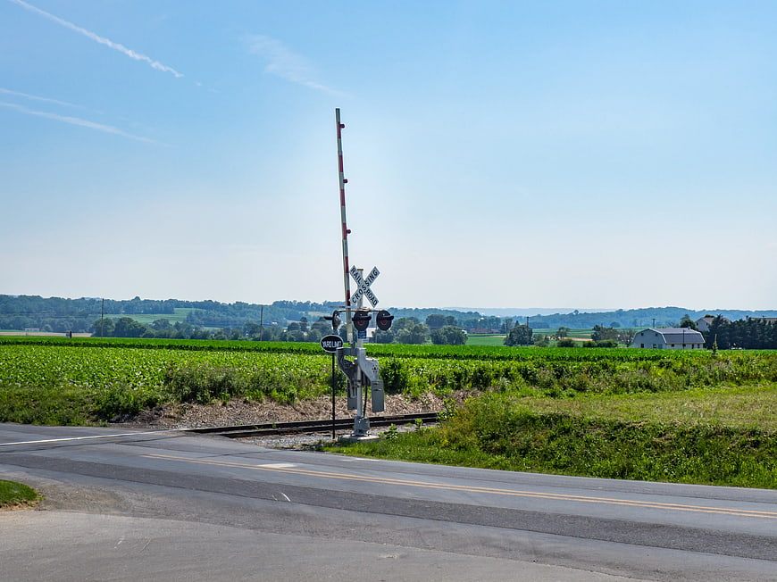 Rural railroad crossing with green fields and blue sky