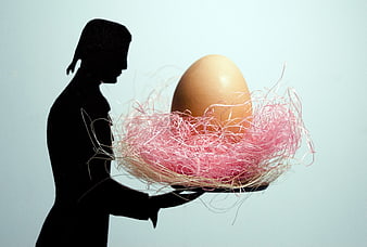 Silhouette of woman holding Easter egg in pink nest