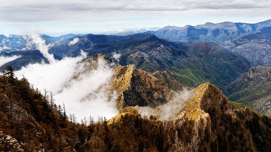 Majestic Mountain Range with Misty Clouds and Forested Peaks
