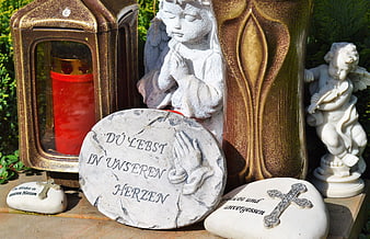 Cemetery memorial with angel statues, red candle, and German inscription stones