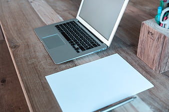 Laptop and blank paper on wooden desk workspace