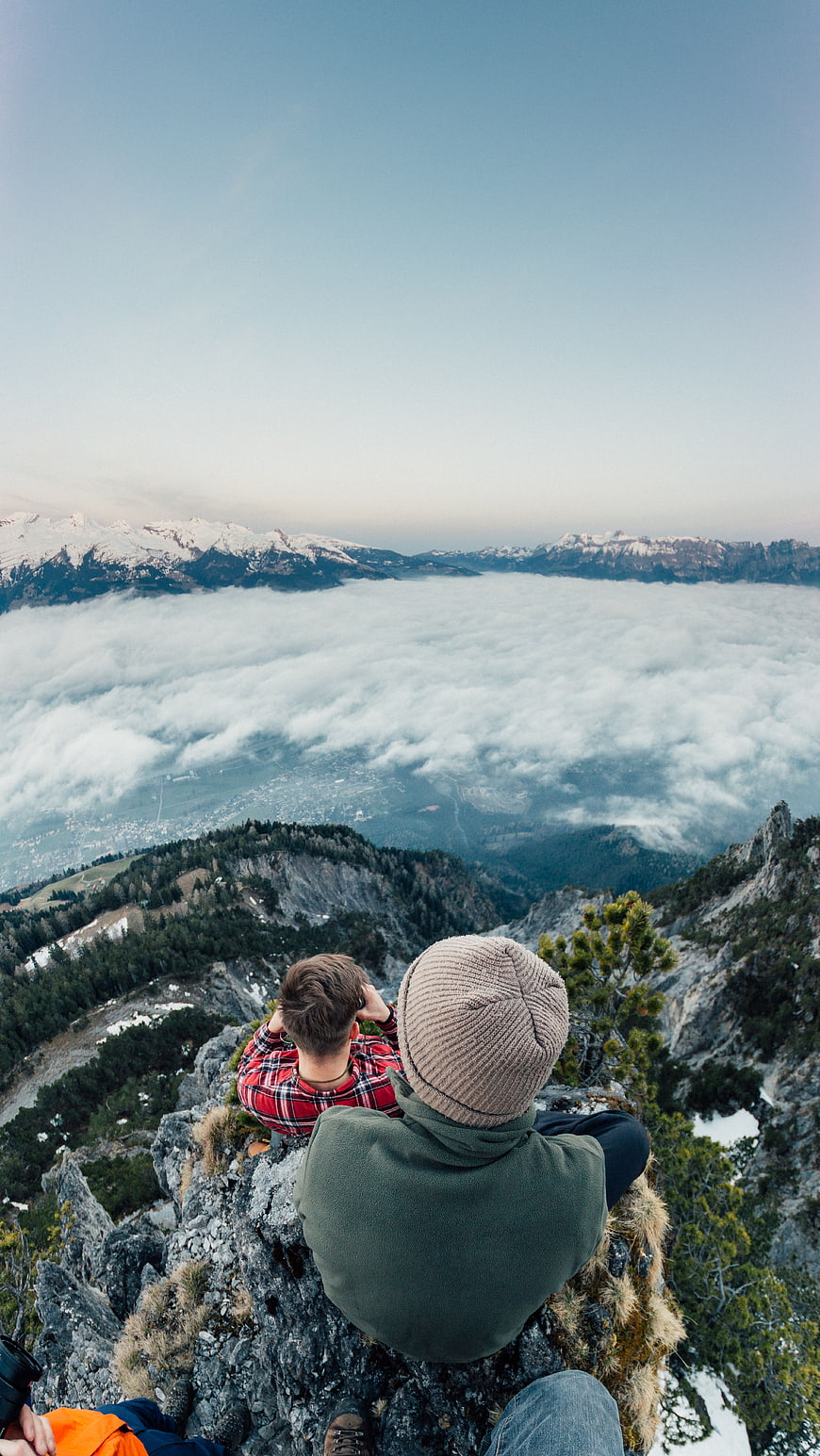 Hikers sitting on mountain peak overlooking sea of clouds