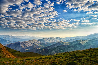 Panoramic View of Green Mountain Ridges Under Blue Cloudy Sky