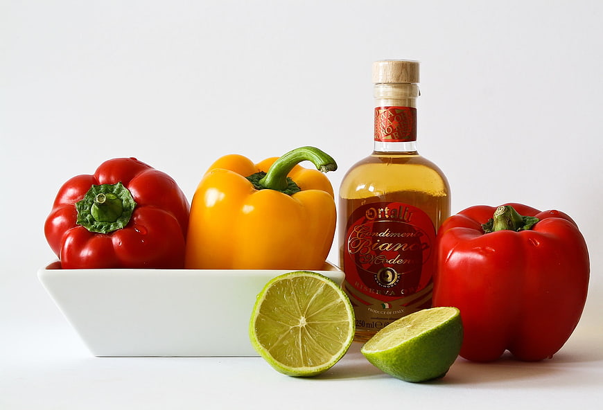 Bell peppers and lime with bottle of Italian white wine on white background