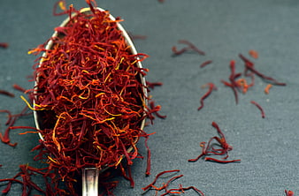 Close-up of saffron threads in a silver spoon on a dark background
