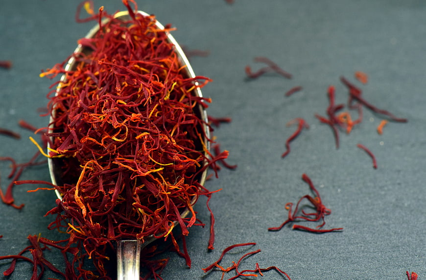 Close-up of saffron threads in a silver spoon on a dark background