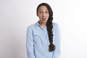 Surprised young woman with long braid in light blue shirt