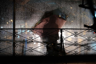 Silhouette of person with umbrella in rain at night