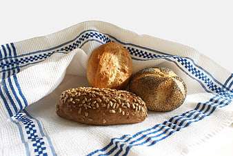 Fresh artisan bread rolls on a blue and white kitchen towel