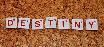 Scrabble tiles spelling DESTINY on a textured cork background
