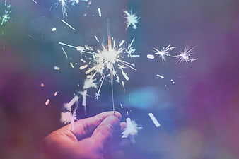 Hand Holding Sparkler with Colorful Bokeh Background