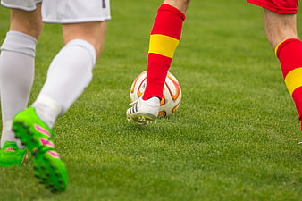 Soccer players competing for ball on green pitch close up