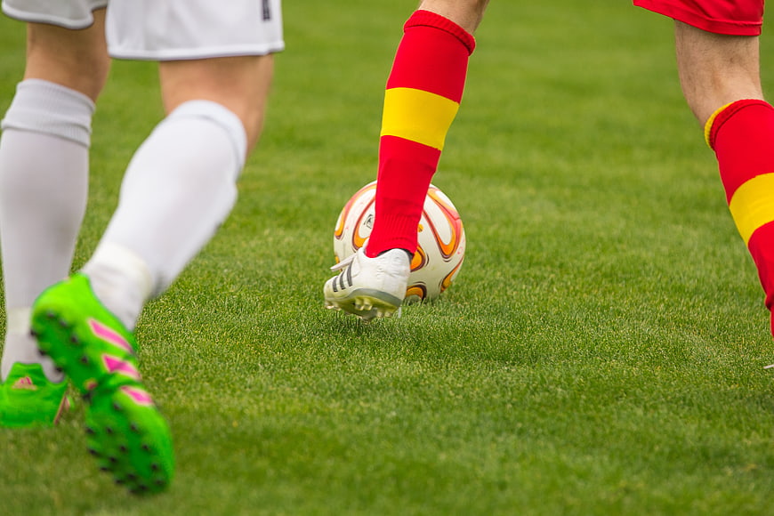 Soccer players competing for ball on green pitch close up