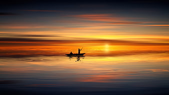 Silhouette of fishermen in a boat on calm sea at sunset