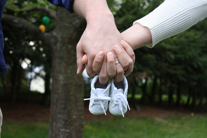 Couple Holding Baby Shoes in Park