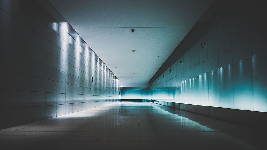 Empty modern corridor with teal lighting and reflections