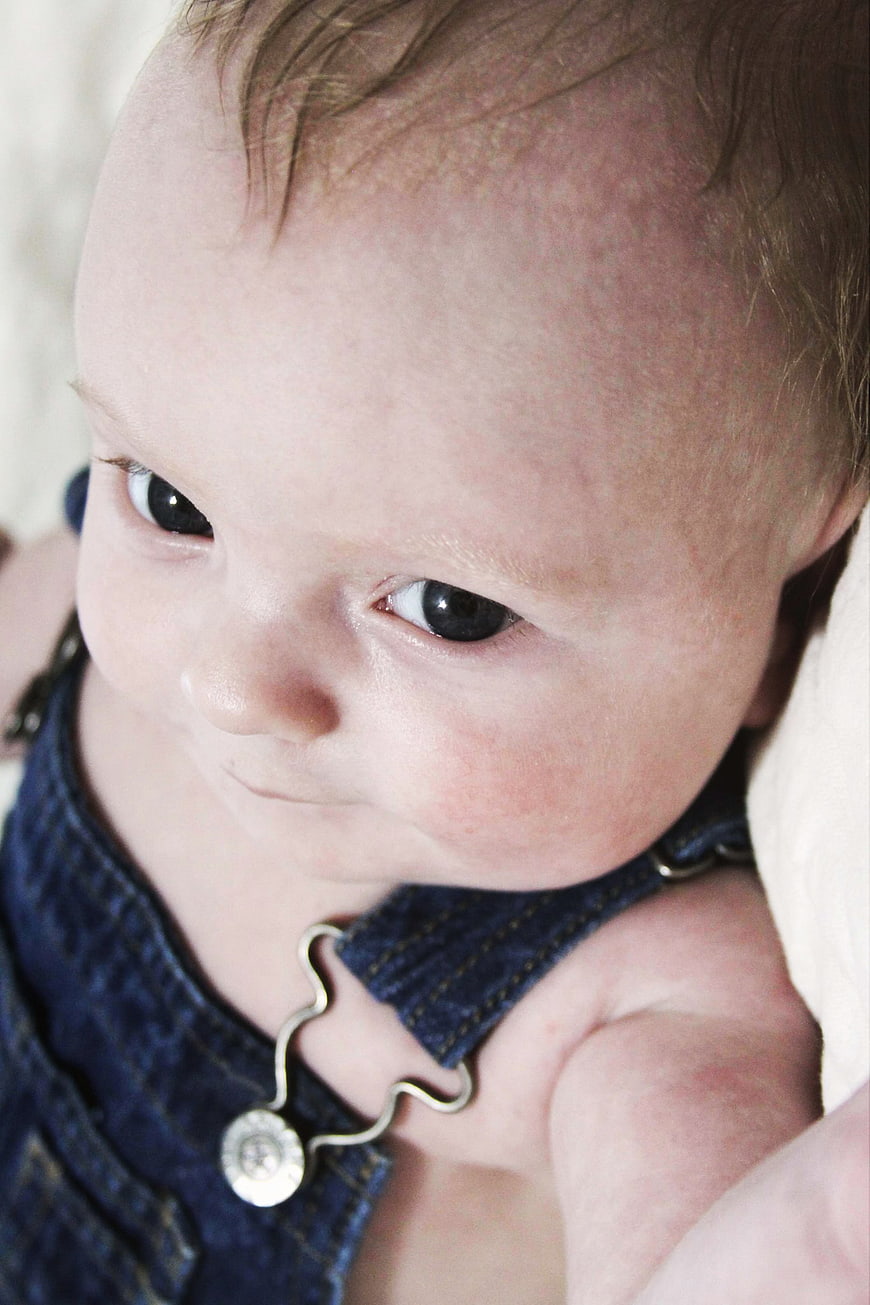 Close-up portrait of a cute baby boy in denim overalls
