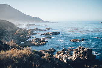 Scenic Rocky Coastline with Blue Ocean and Distant Mountains