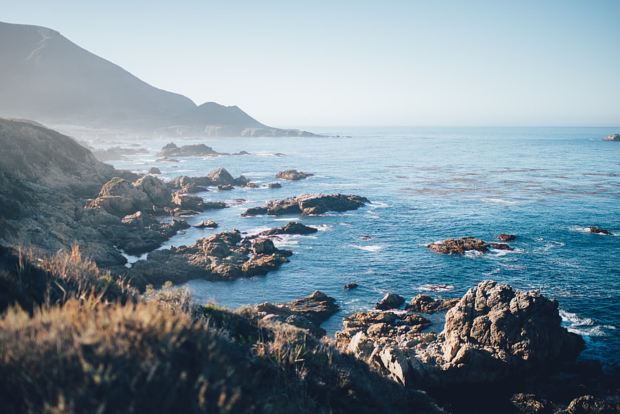 Scenic Rocky Coastline with Blue Ocean and Distant Mountains