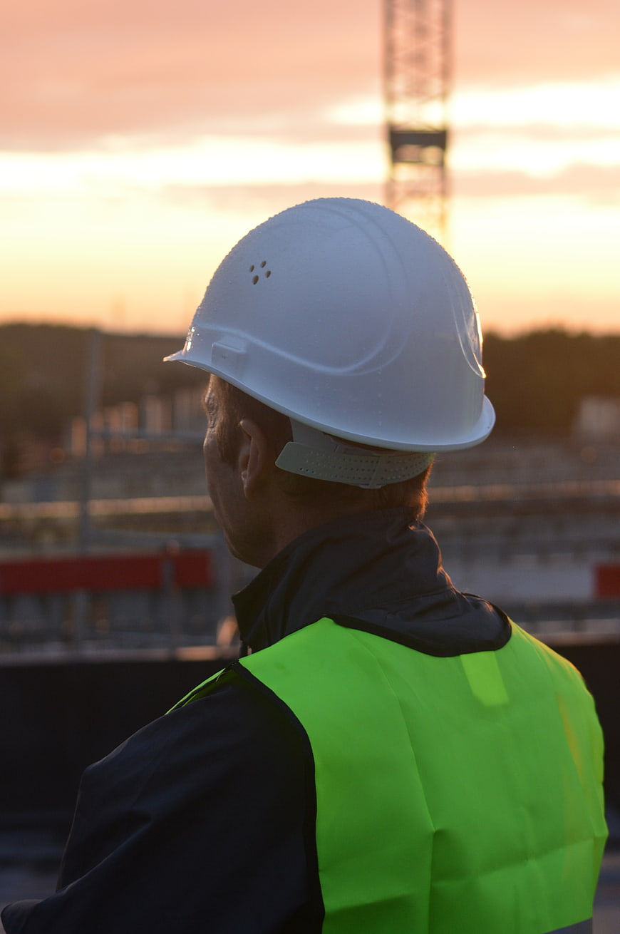 Construction worker in safety vest and helmet at sunset