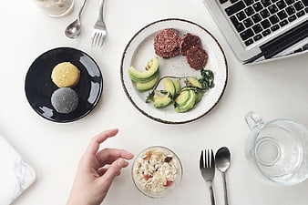 Overhead view of healthy lunch with avocado and laptop
