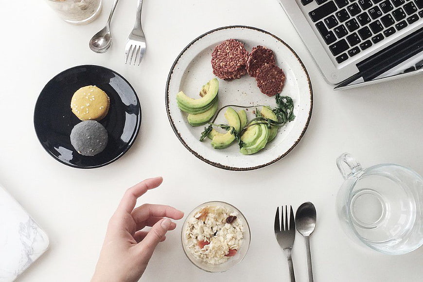 Overhead view of healthy lunch with avocado and laptop