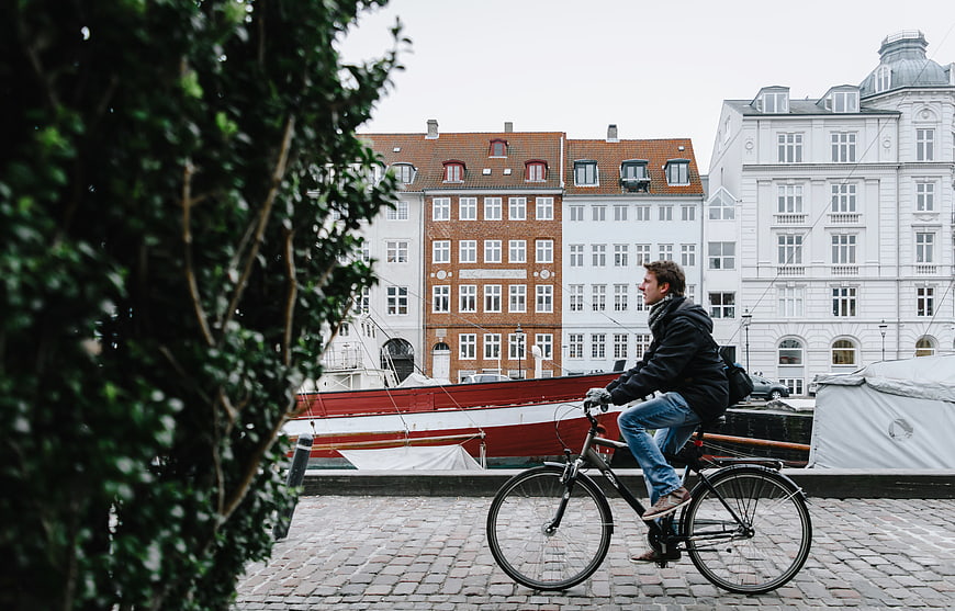 Man Cycling Past Historic European Canal Buildings