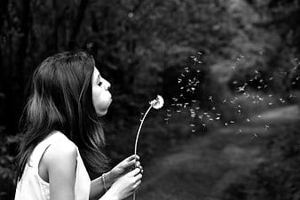 Woman Blowing Dandelion Seeds in Black and White