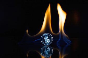 Silver Coin with Flame on Black Reflective Surface